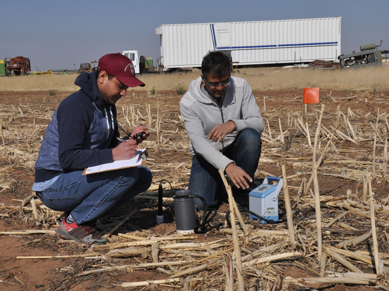 Dos hombres recogiendo medidas del suelo en el campo.
